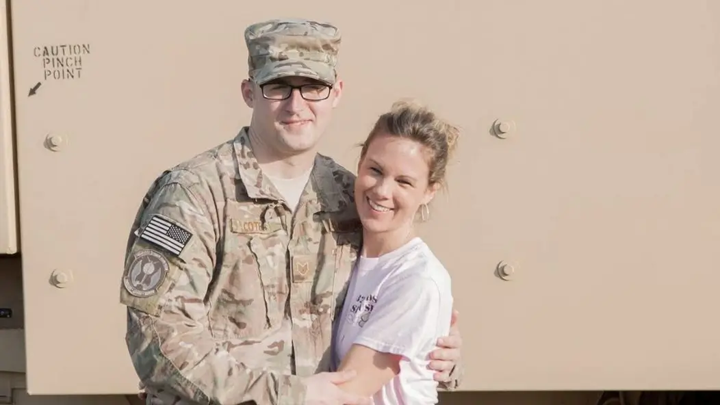 U.S. Air Force veteran David Cote stands beside his wife before deploying to Afghanistan, both smiling and embracing in front of a military vehicle.